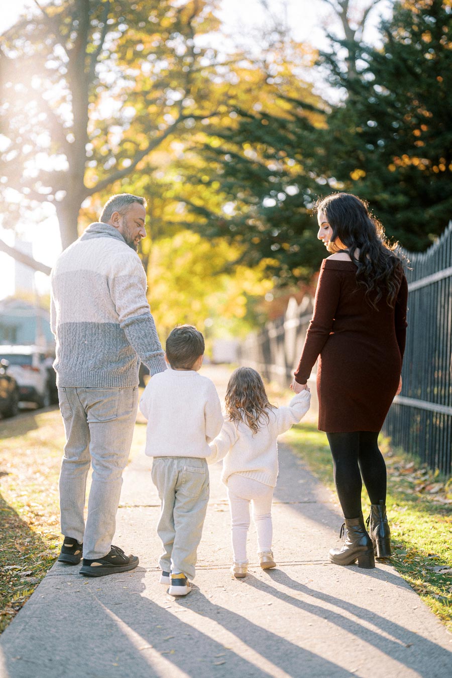 A family walking hand in hand on a sunny autumn day, surrounded by colorful trees and soft sunlight, conveying warmth and togetherness.