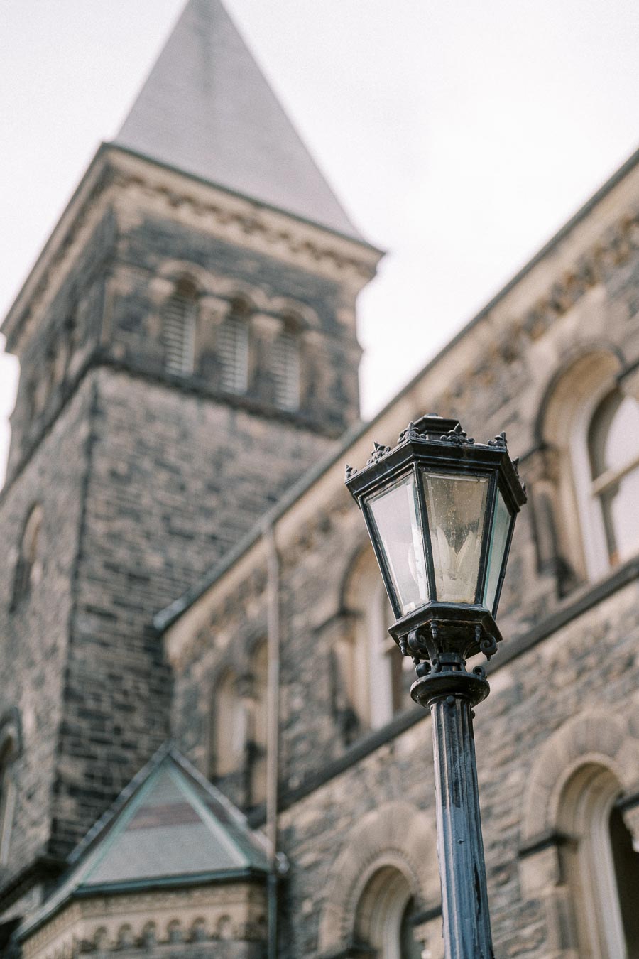Ornate street lamp with stone Gothic architecture background, featuring pointed tower and arched windows