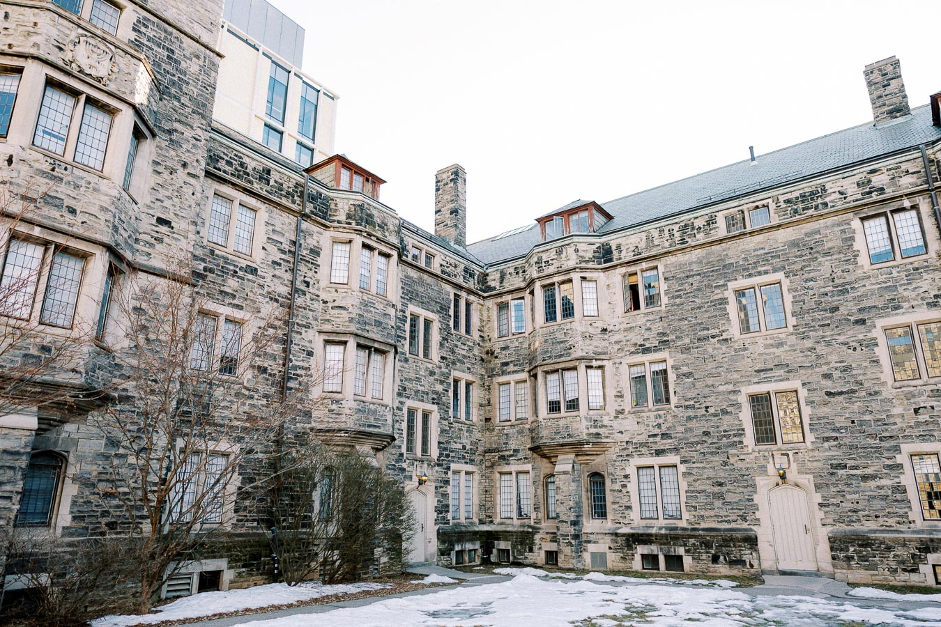 Historic stone building with multiple windows and snow-covered ground, showcasing architectural details and winter scenery.