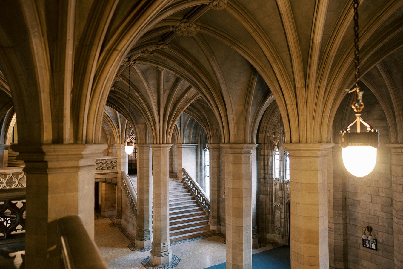 Interior view of a historic building featuring stone arches, elegant columns, and a grand staircase with intricate