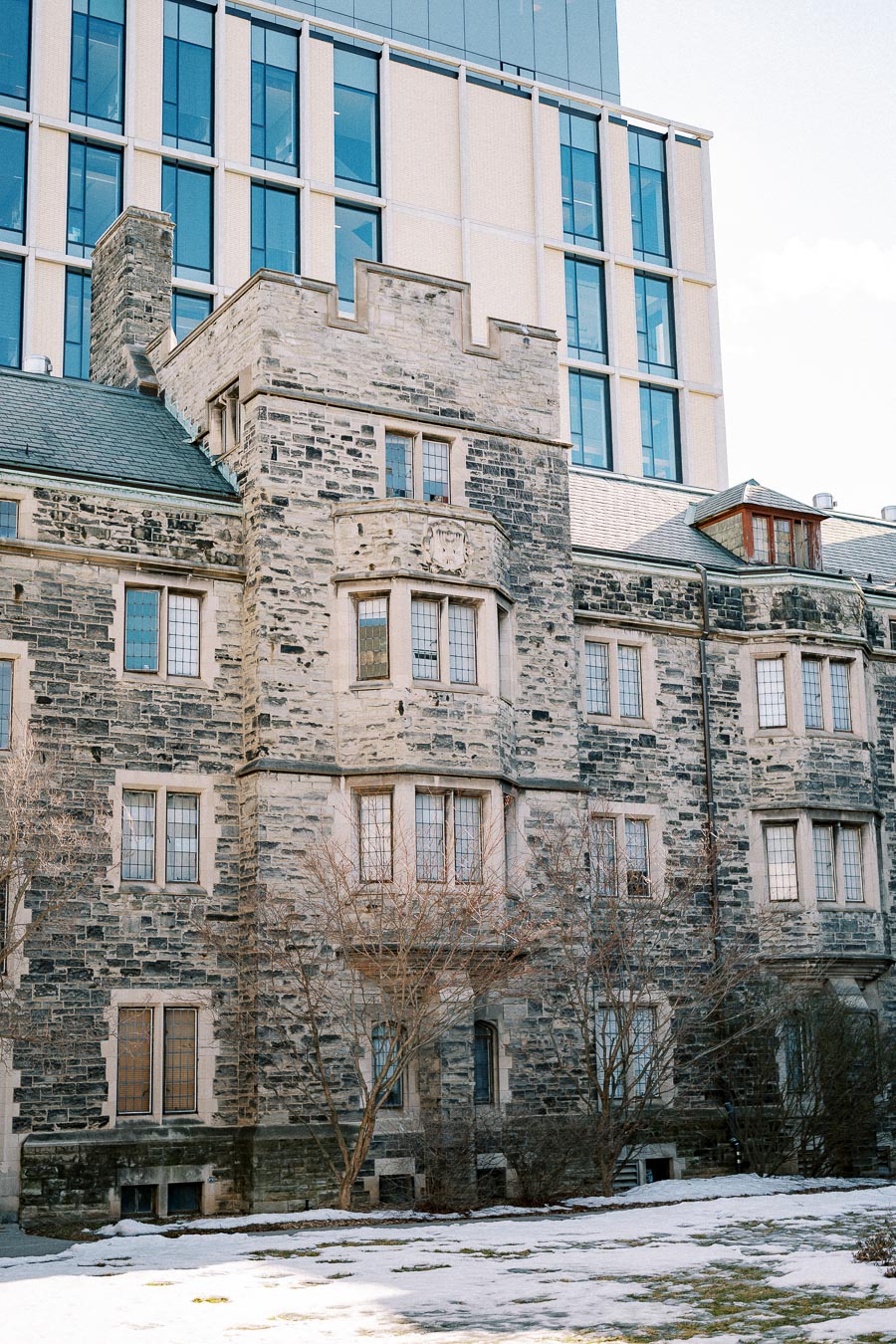 Historic stone building with gothic architecture, featuring arched windows and a modern glass structure in the