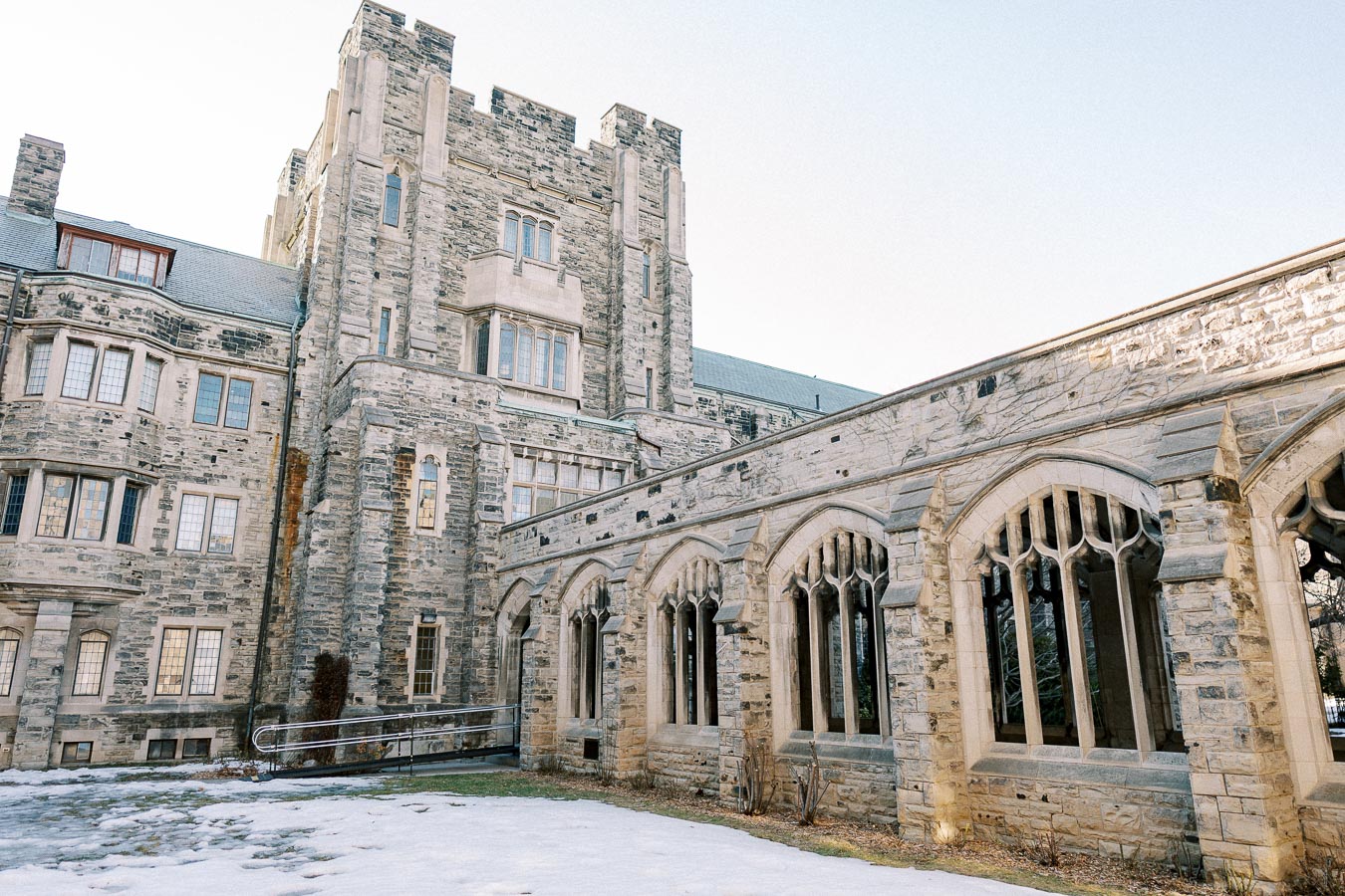 Historic stone building with gothic architecture featuring arched windows, surrounded by a snowy landscape under a