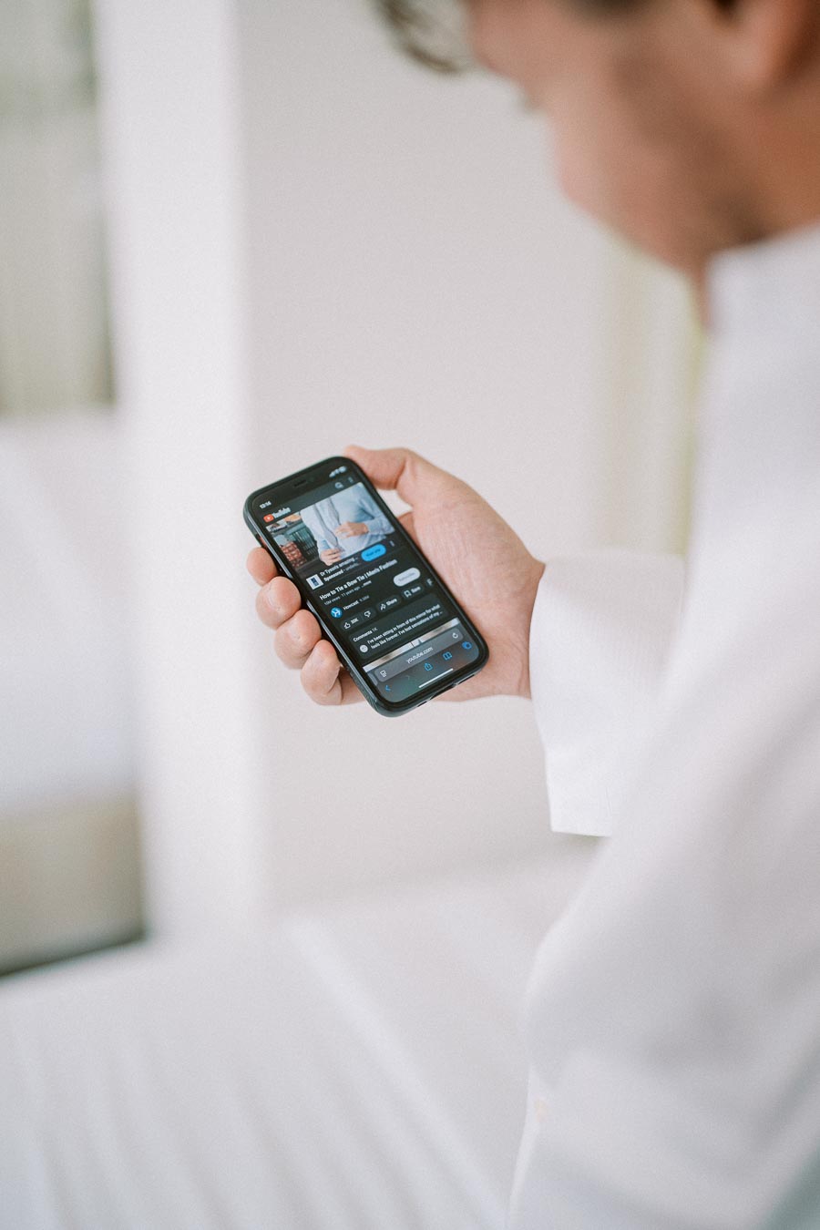 A person holding a smartphone displaying a video in a brightly lit room, emphasizing mobile technology and digital media consumption.