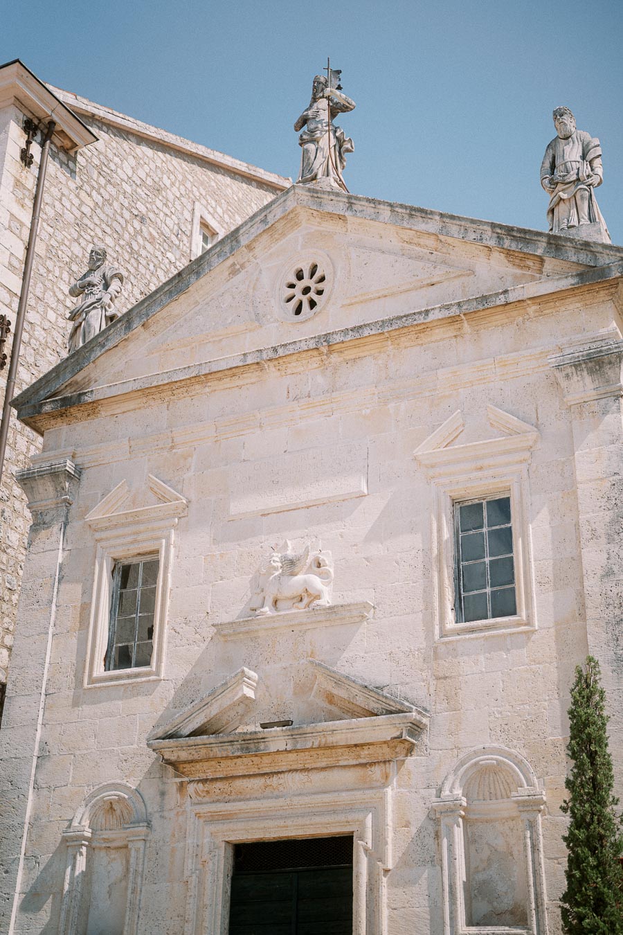 Historic stone church facade with intricate carvings and statues in sunny weather, showcasing architectural details and cultural heritage