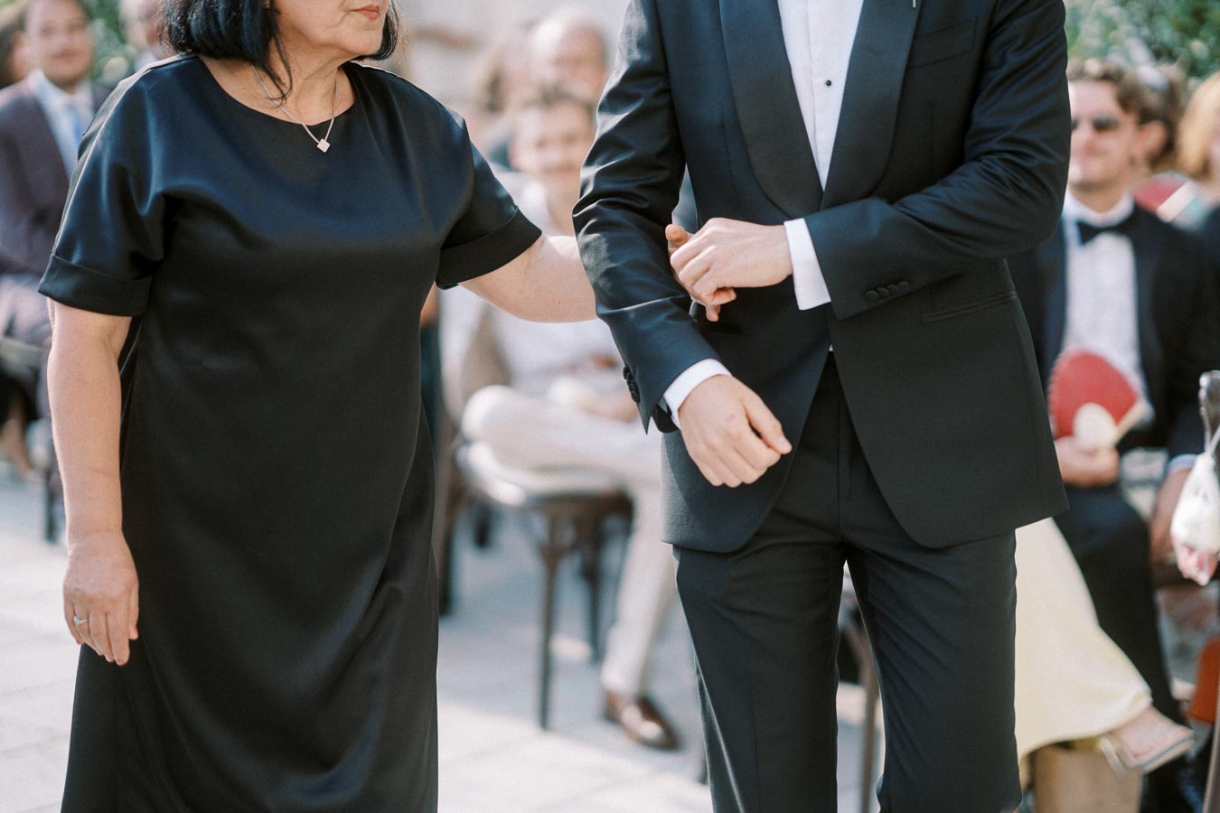 A woman in a black dress and a man in a suit walking arm in arm during a formal event.