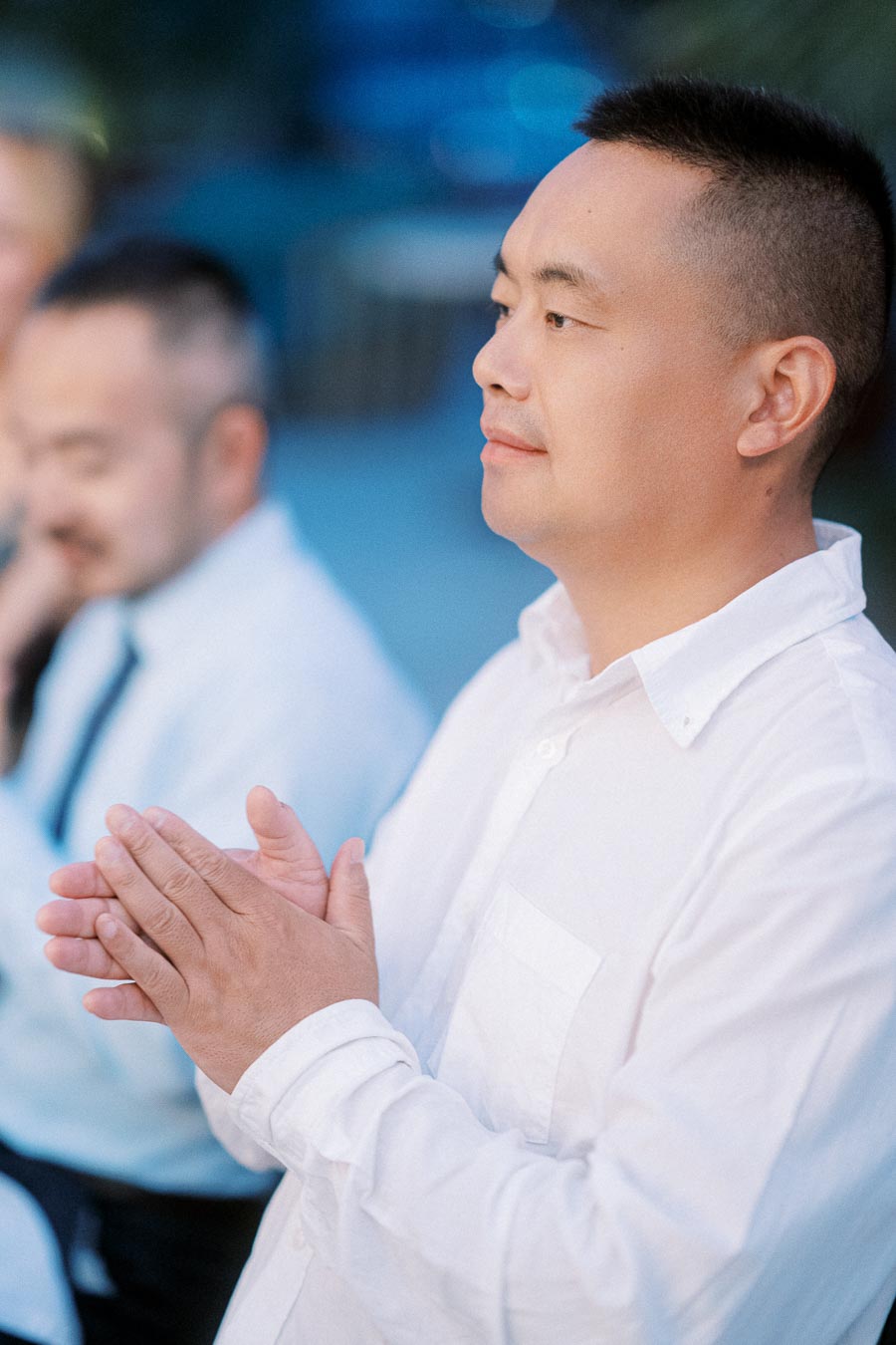 A person in a white shirt clapping at an outdoor event, showing appreciation and engagement.