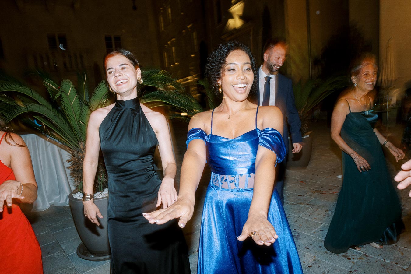 Group of people celebrating and dancing in elegant evening attire at an outdoor party.