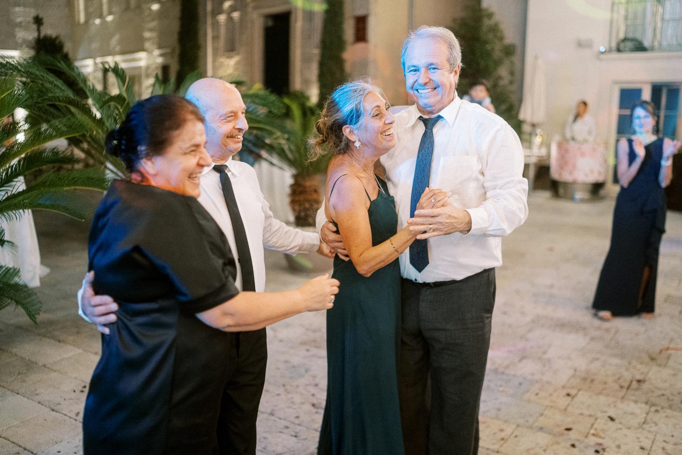 Senior couples joyfully dancing at an outdoor evening event, surrounded by lush greenery and soft lighting.