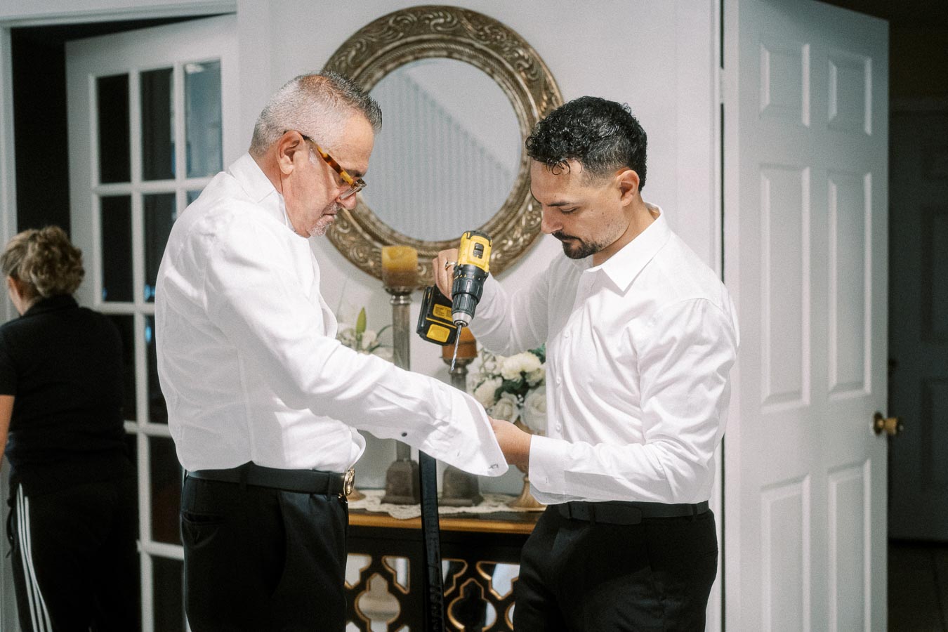 Father and son dressed in white shirts using an electric drill for home improvement in a modern living space with decorative