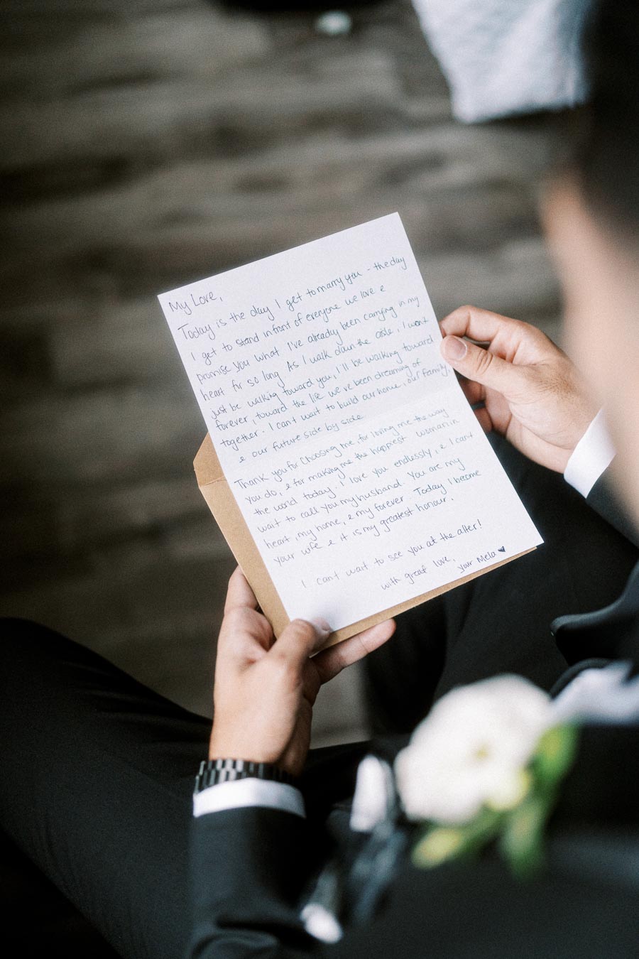 A groom holding a handwritten wedding day love letter, expressing tender emotions and anticipation, dressed in a suit with a