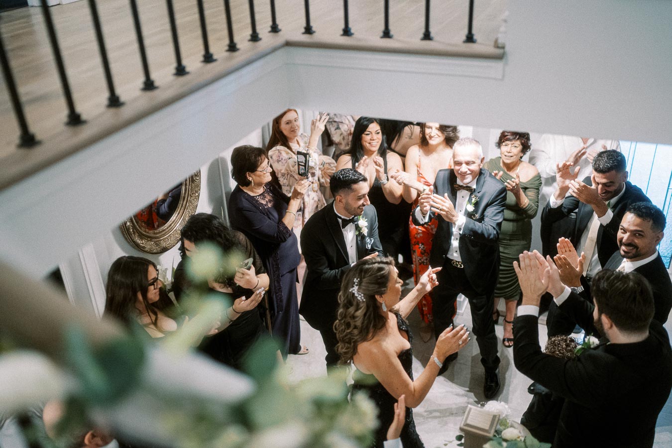 Group of elegantly dressed people celebrating at a wedding reception, clapping and smiling in a lively and joyful atmosphere.