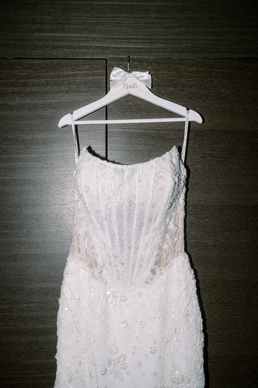 Elegant white lace wedding dress with intricate detailing on a personalized hanger marked Bride.