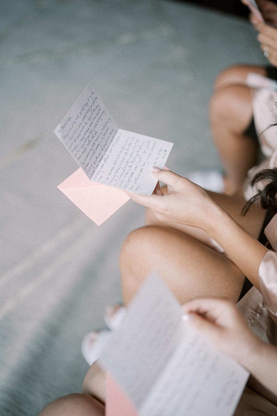 A person reading a handwritten letter, with delicate pink envelope visible, conveying a personal and heartfelt message.