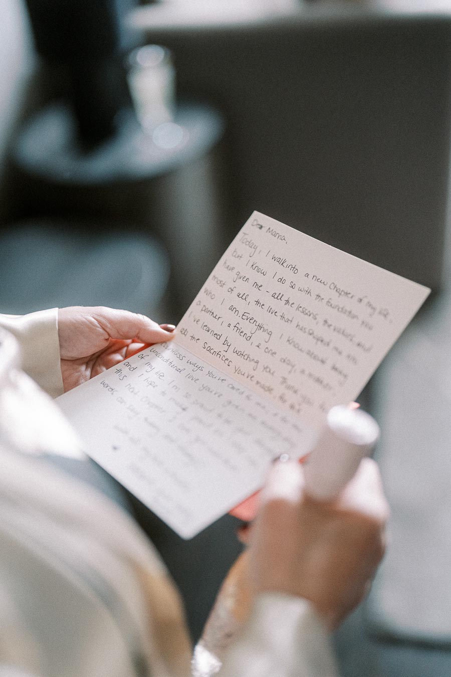 A person holding a handwritten letter with a heartfelt message, focusing on sentimental words, in a softly lit room.