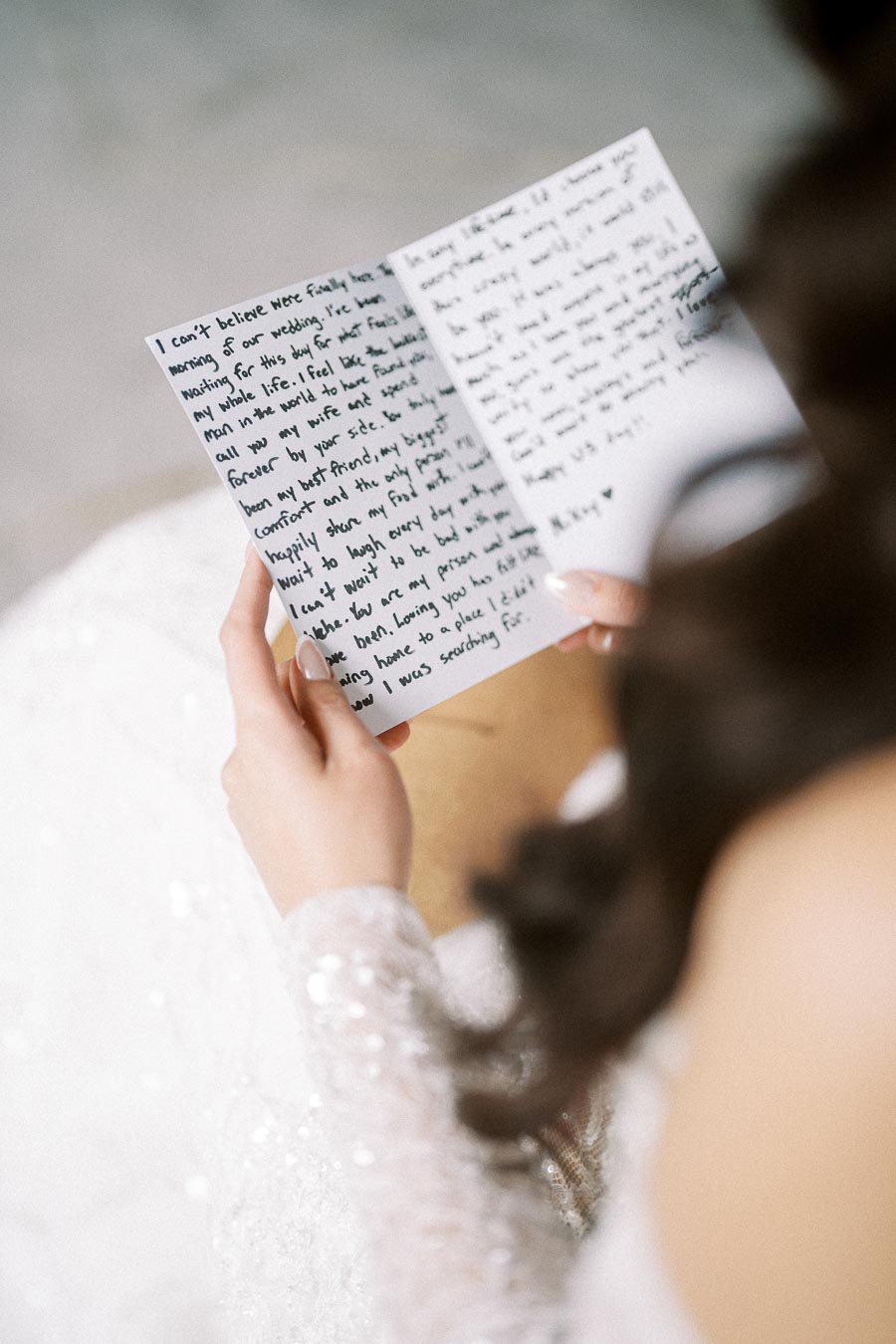 A bride holding and reading an emotional handwritten wedding letter, capturing a heartfelt moment on her special day.