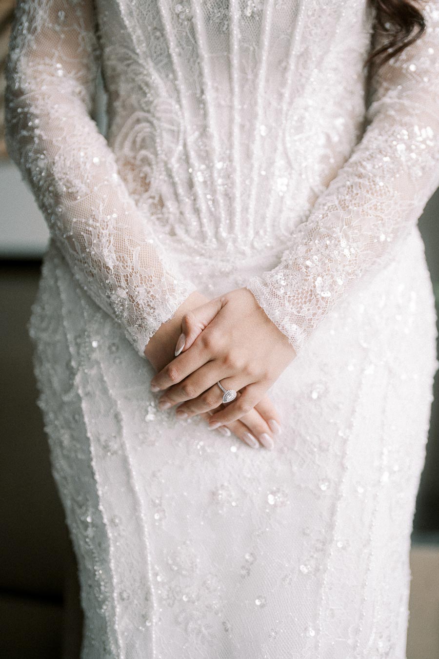 Elegant Close-up of a Bride in a Lace Wedding Dress Featuring Intricate Embroidery and a Sparkling Engagement Ring.