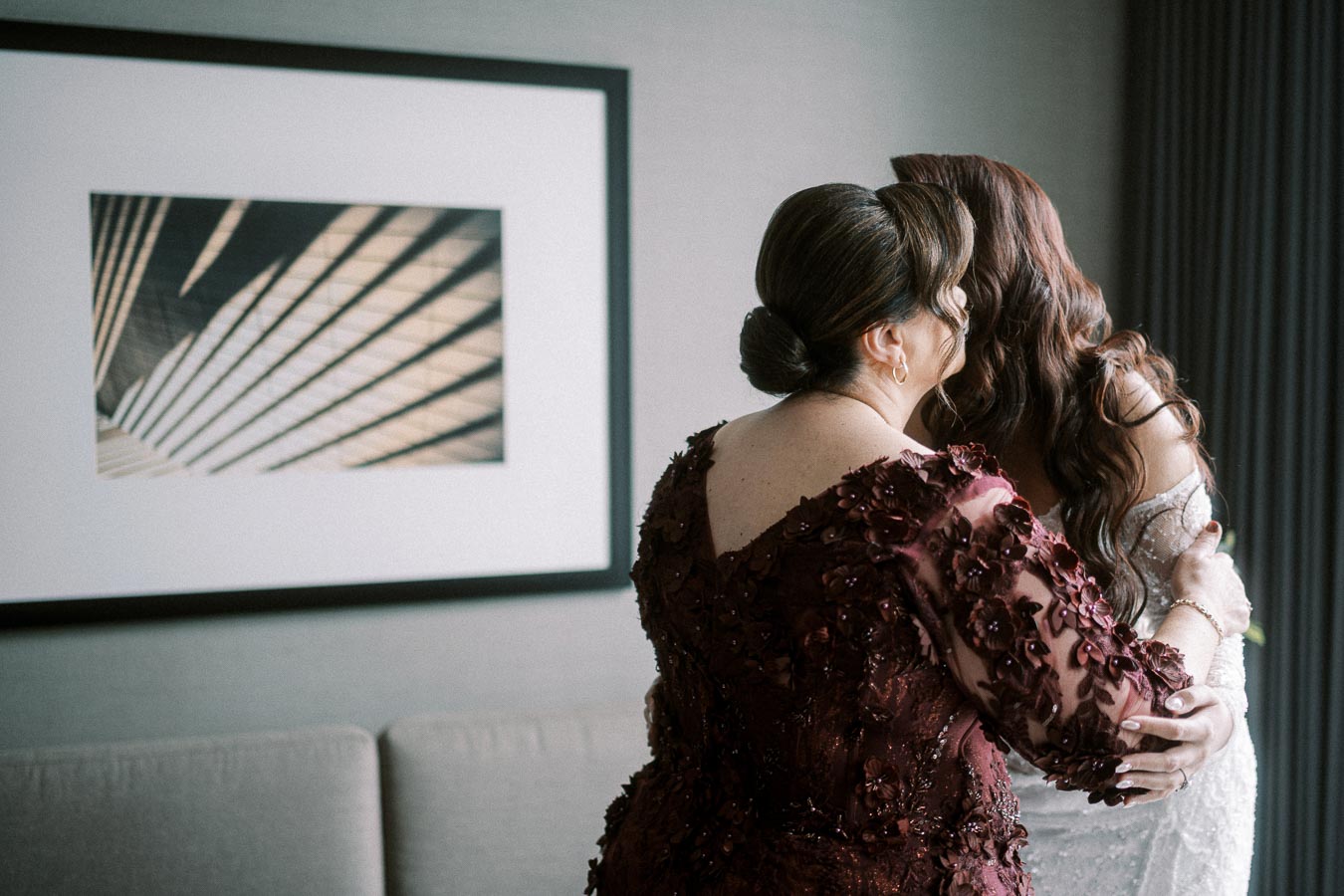 A mother in an elegant embroidered dress hugging her daughter, the bride, in her bridal gown, creating a touching moment