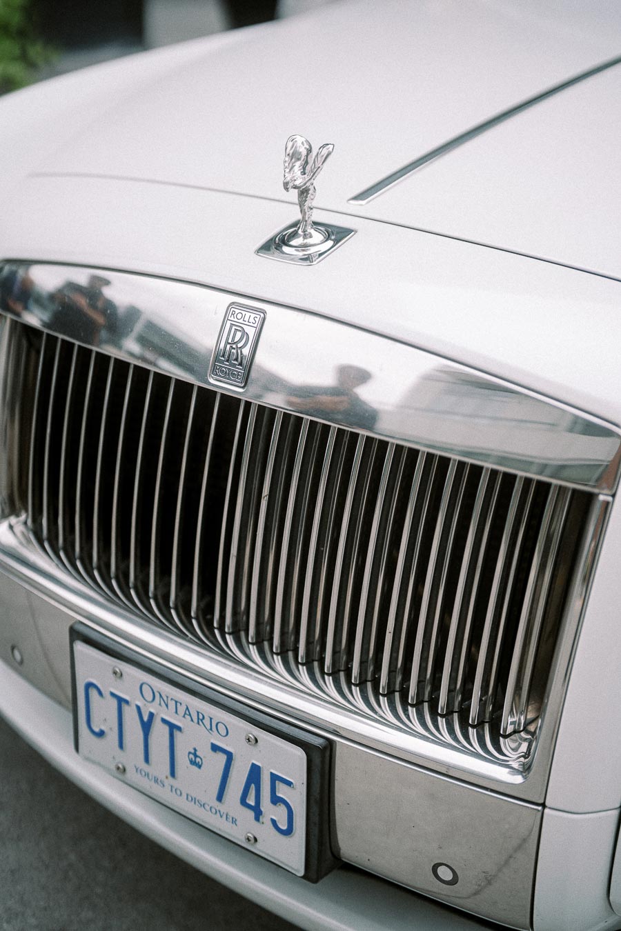 Front view of a luxury Rolls-Royce car showcasing its iconic silver grille and Spirit of Ecstasy hood ornament, with an