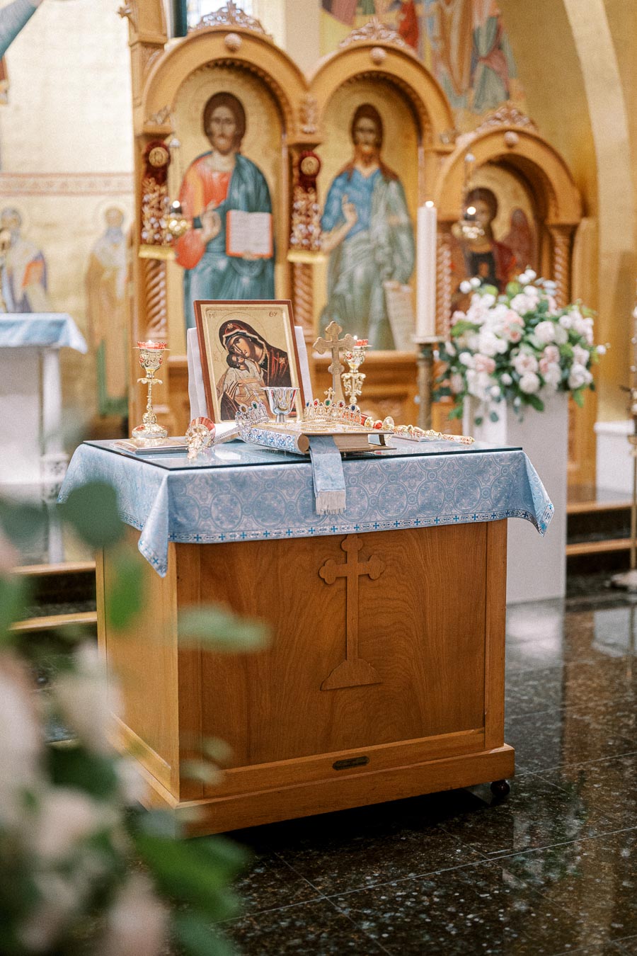 Orthodox church altar with icons and religious artifacts, featuring a cross-engraved wooden table covered in a