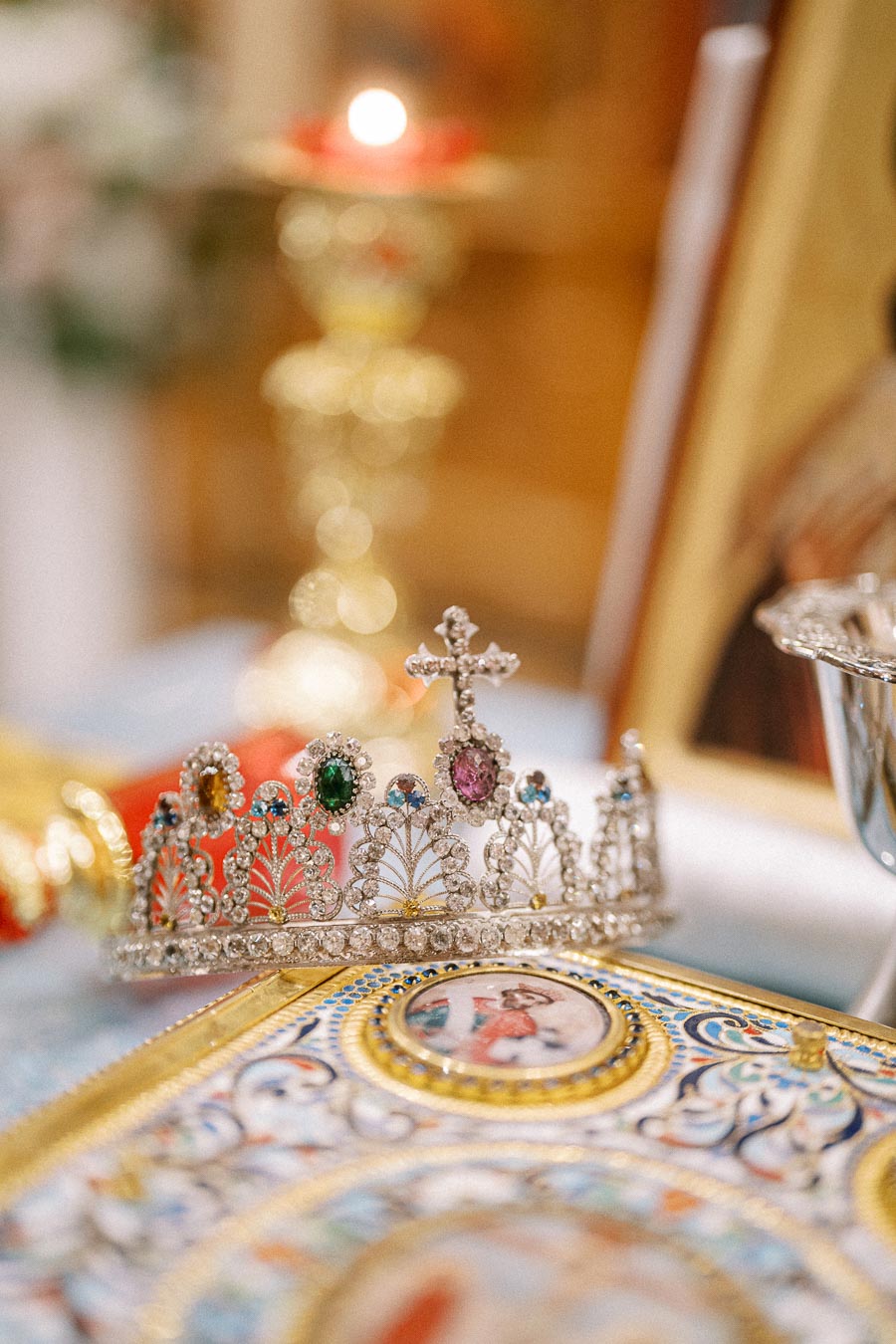 Close-up of an ornate jeweled crown with colorful gemstones on a decorative book, featuring intricate detail and a