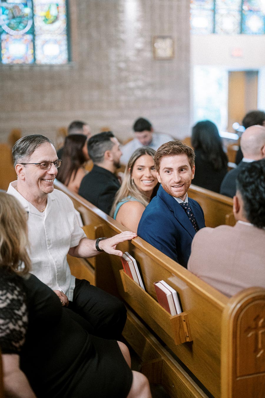 People sitting in pews at a church event, smiling and interacting with each other.