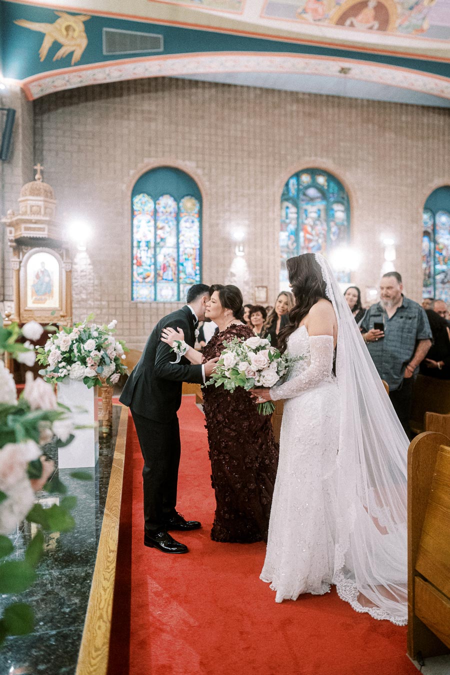 Wedding ceremony in a beautifully decorated church, featuring a bride in an elegant white gown and long veil, holding a