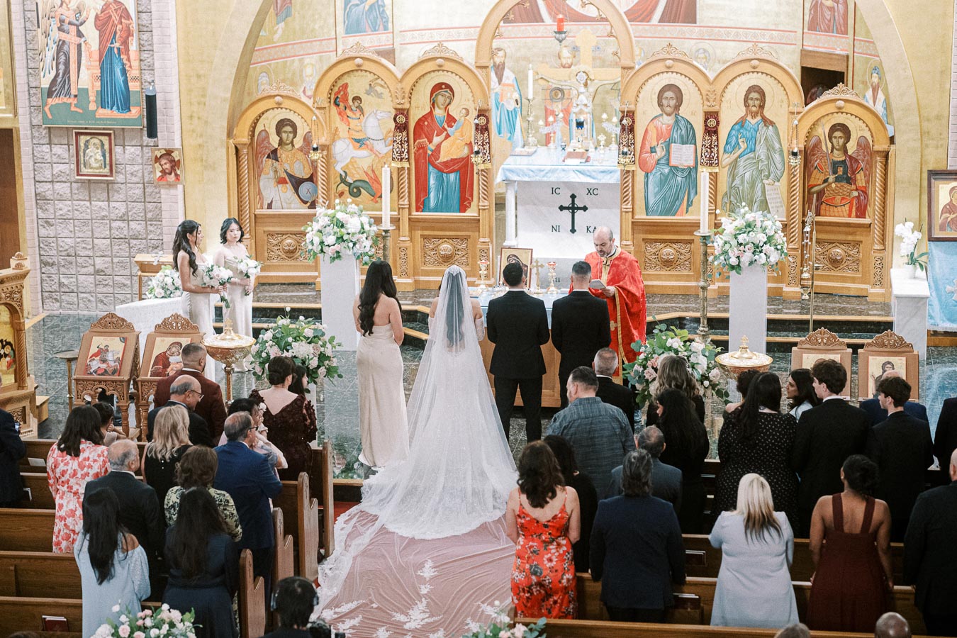 Orthodox wedding ceremony taking place in a beautifully decorated church, with a bride in a long white gown and veil