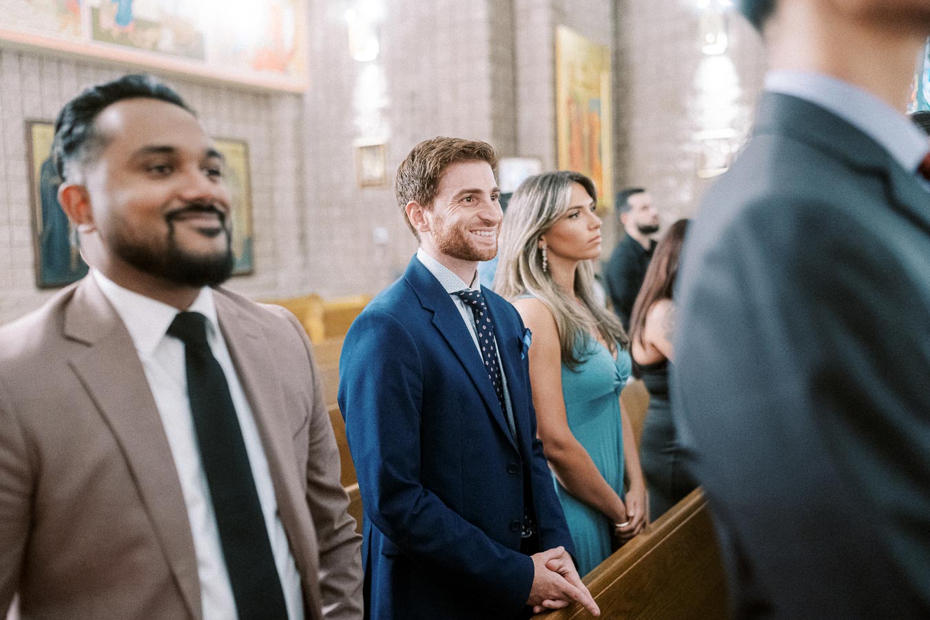 A group of well-dressed individuals smiling and standing inside a church, attending a formal event or ceremony, with focus