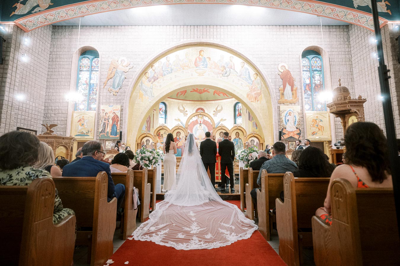 Bride and groom stand at the altar during their wedding ceremony in a beautifully decorated church with ornate