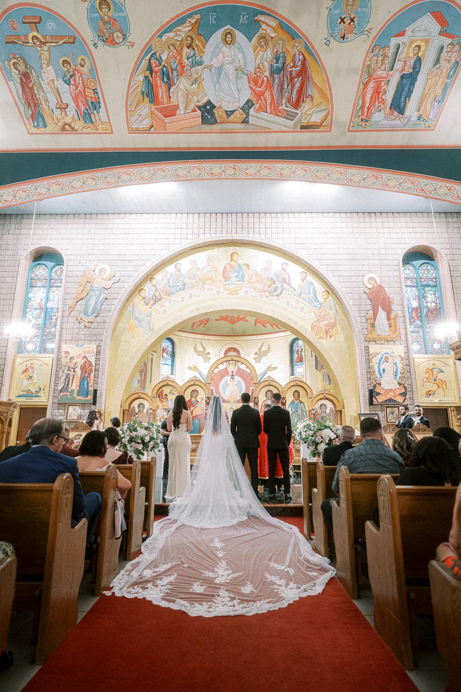 Traditional wedding ceremony in a richly decorated church with vivid murals on the walls and ceiling, featuring a