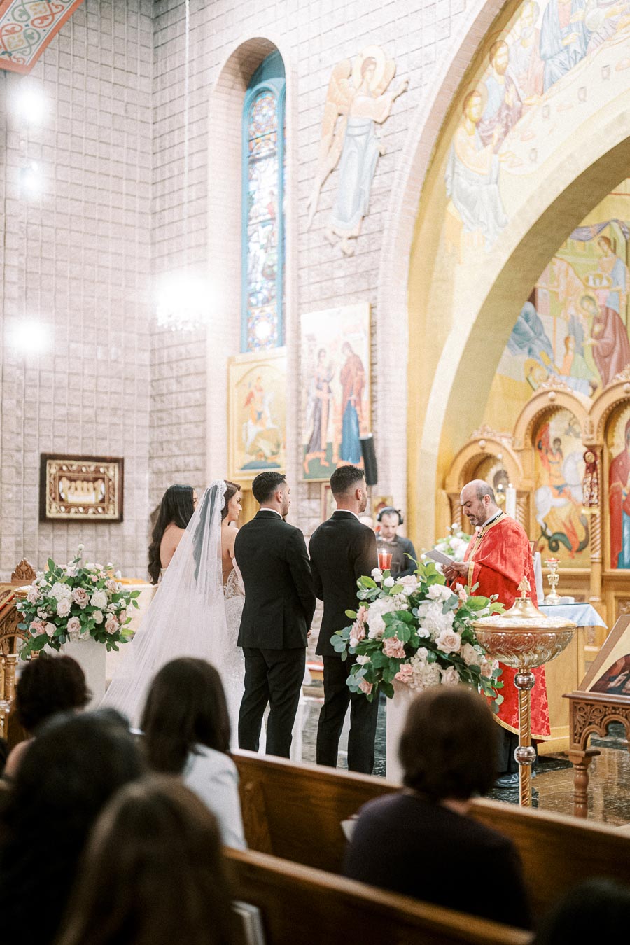 A bride and groom stand at the altar in a beautifully decorated church, exchanging vows during a wedding ceremony. The scene