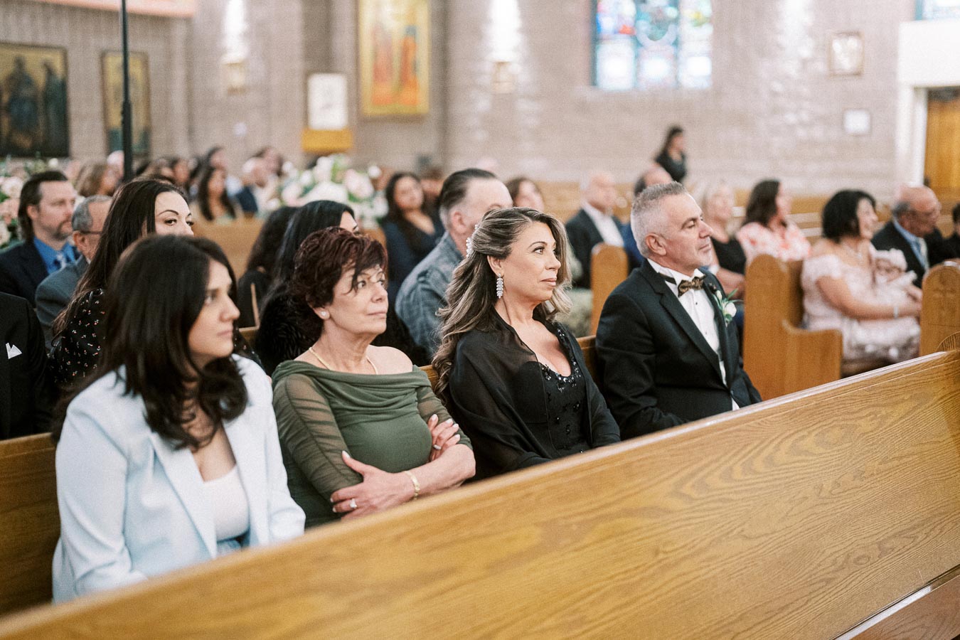 A group of well-dressed guests seated in pews at a formal church event, showcasing a diverse and attentive audience in an
