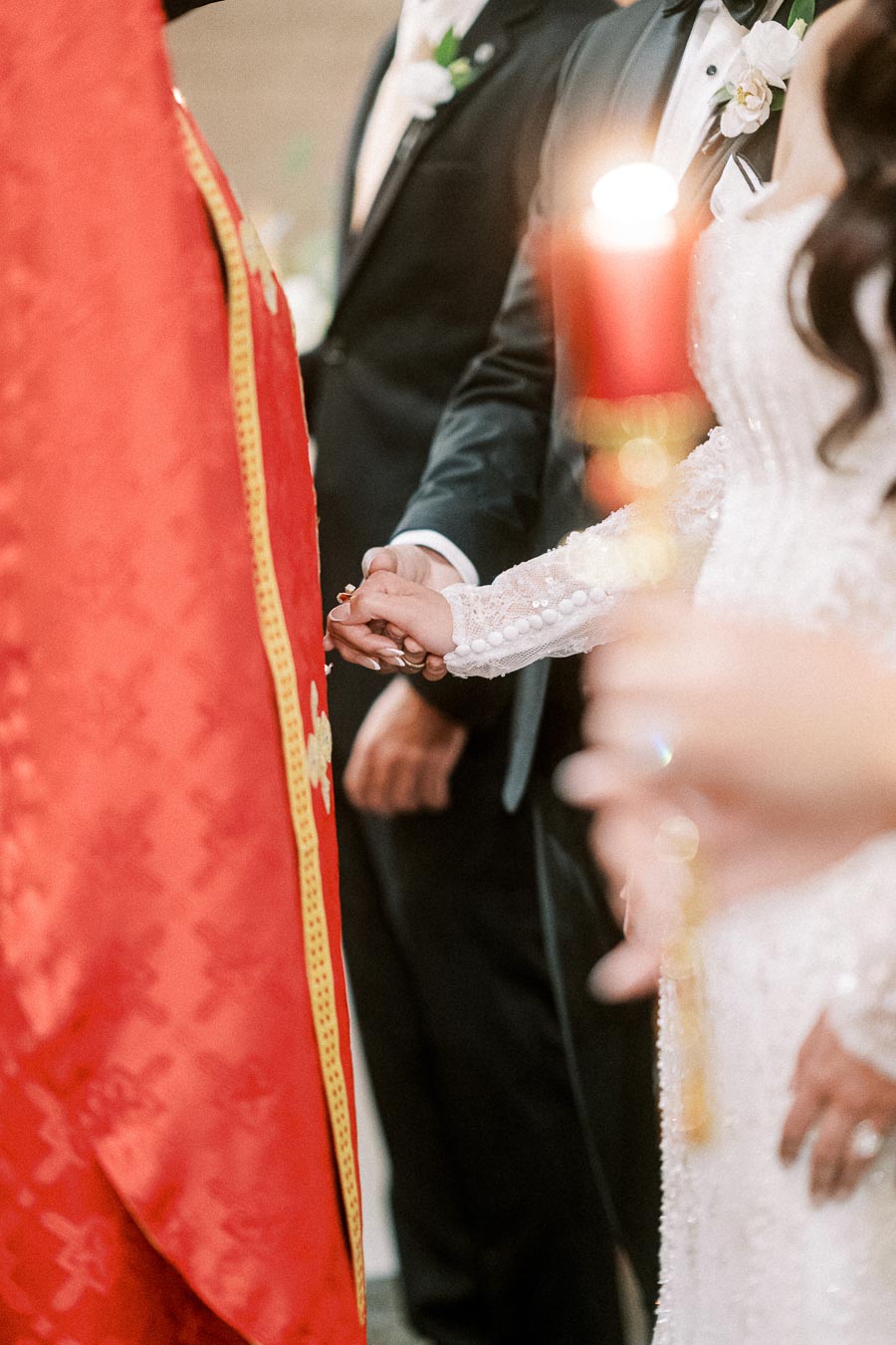 Close-up of a couple holding hands during an intimate wedding ceremony, with the bride wearing a lace dress and groom in a