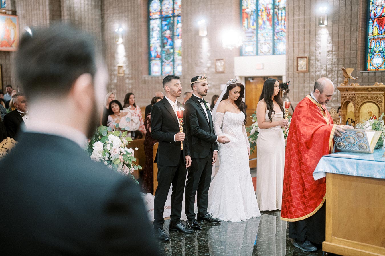Wedding ceremony in a beautifully decorated church, featuring a bride in a white gown and groom in a black suit, accompanied