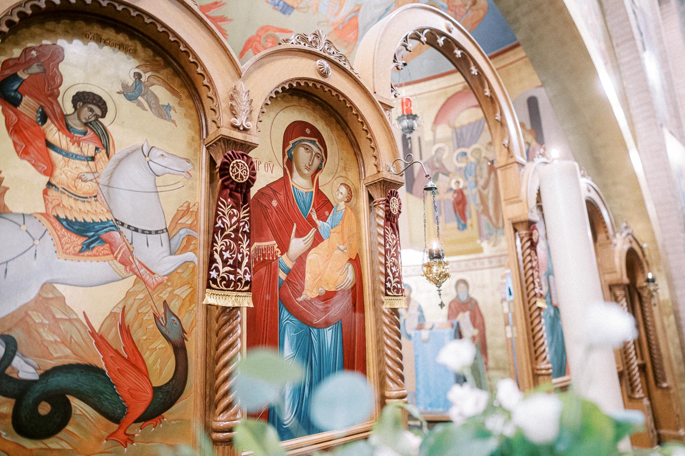 Orthodox church interior showcasing vibrant religious iconography, including a saint on horseback and a depiction of the