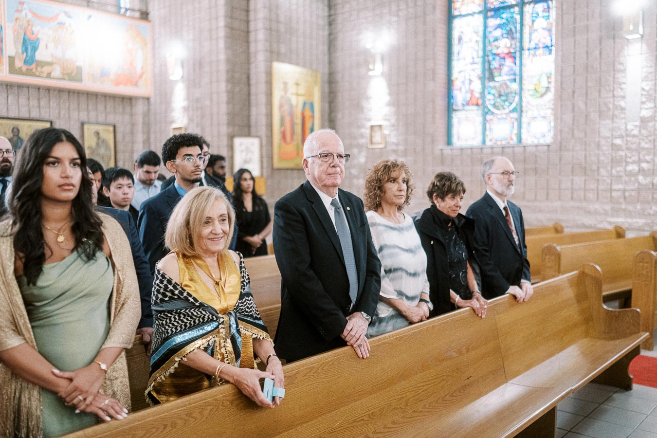 A diverse group of people attending a church service, standing in pews and observing a ceremony inside a beautifully
