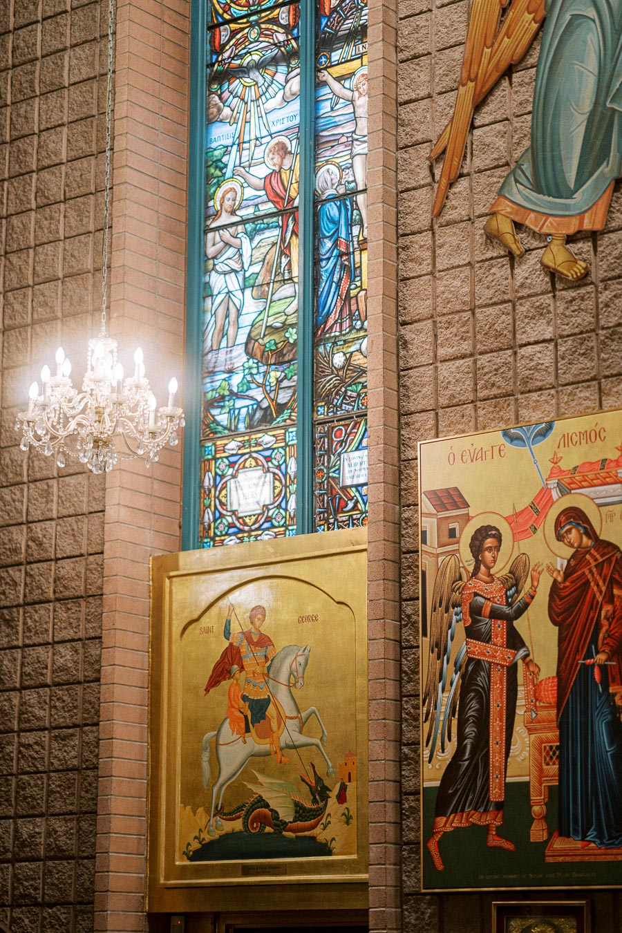 Stained glass window and religious icons inside a church, featuring detailed artwork of biblical scenes and figures, with a