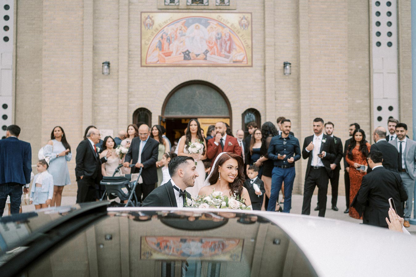 Bride and groom leaving a church after their wedding ceremony, surrounded by family and friends, with smiles and joy on