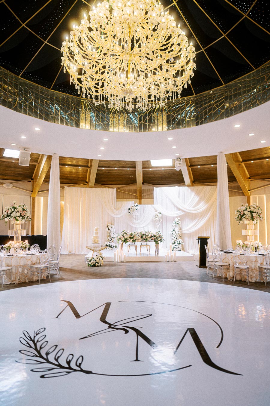 Luxurious wedding reception hall with elegant decor, featuring a grand chandelier, beautifully arranged floral centerpieces,