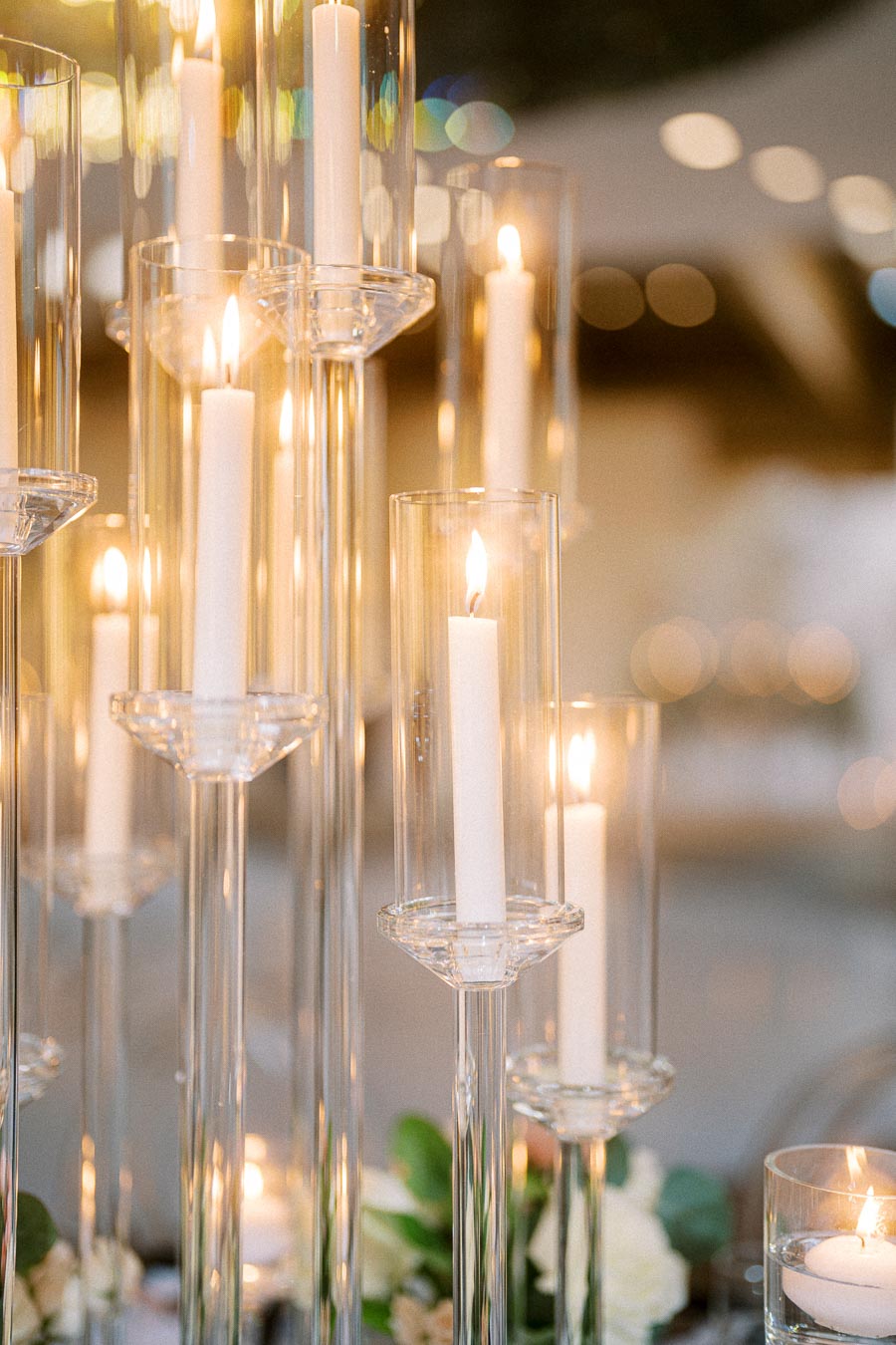 Elegant tall glass candle holders with lit white candles create a warm glow, enhancing the ambiance of a sophisticated event