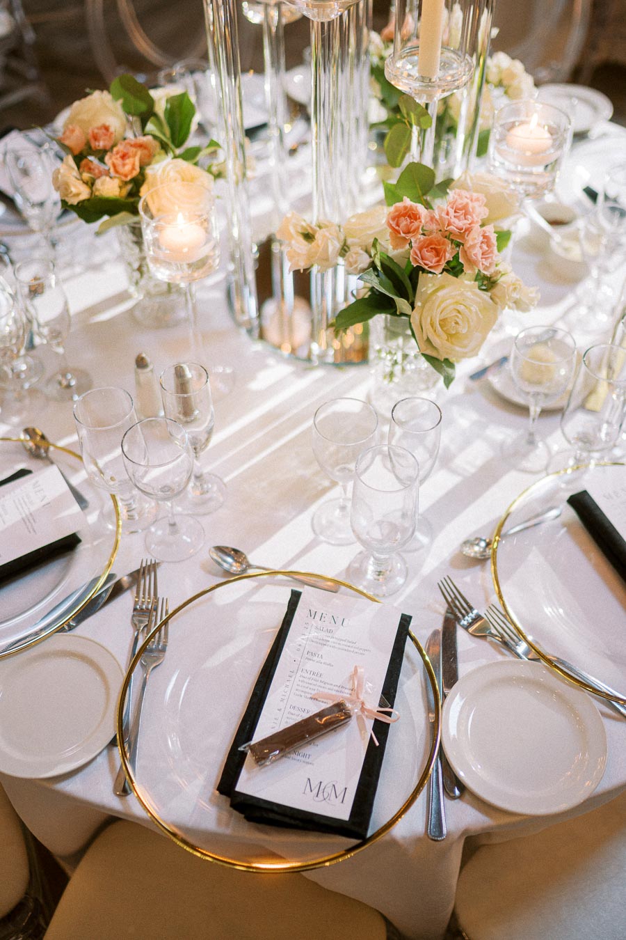 Elegant wedding table setting with floral centerpieces, gold-rimmed plates, glassware, and menu cards, creating a