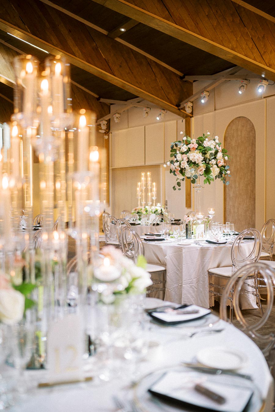 Elegant wedding reception setup with beautifully arranged round tables adorned with white tablecloths and floral