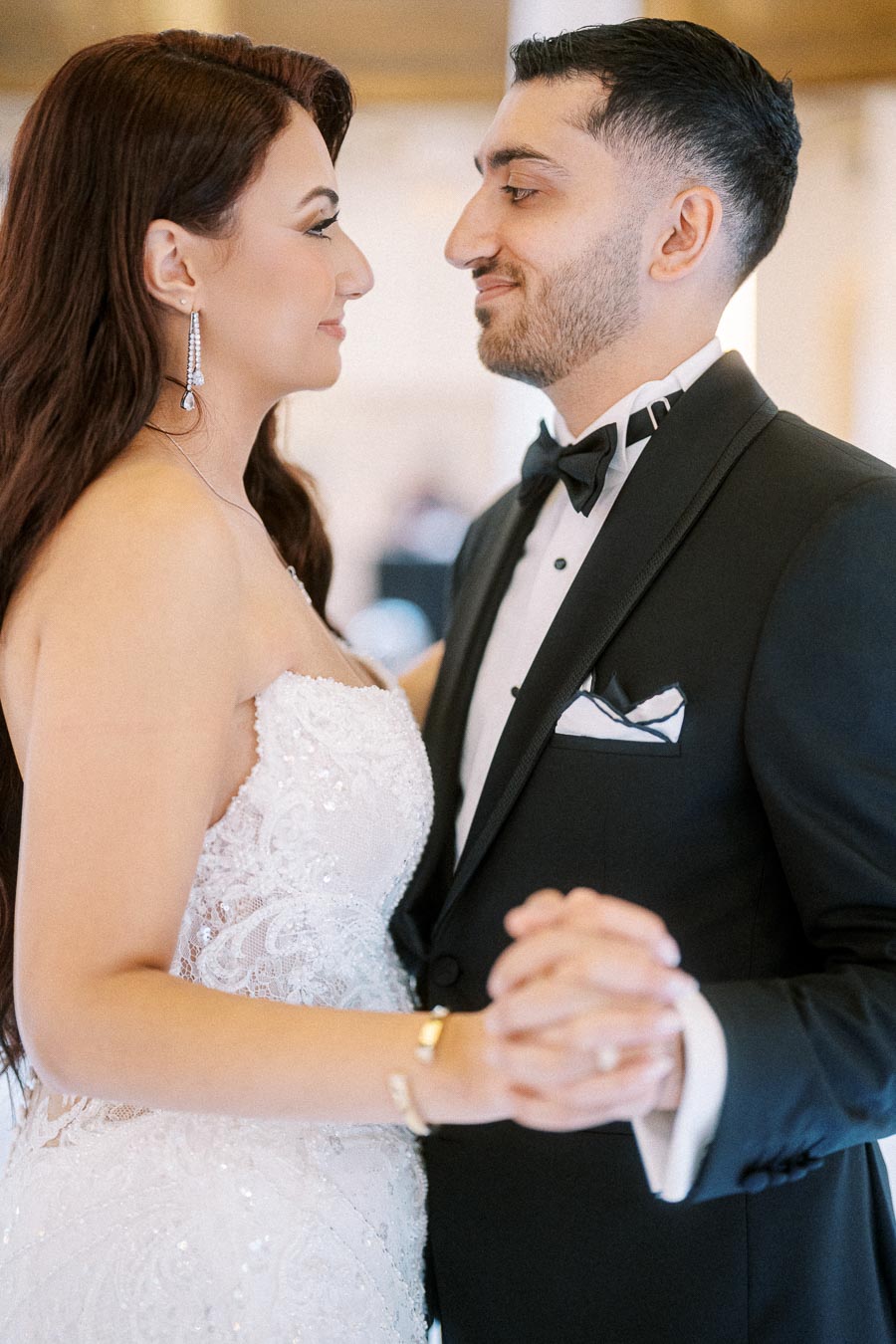 Wedding couple sharing a romantic dance in elegant attire, with the bride in a white lace gown and the groom in a black