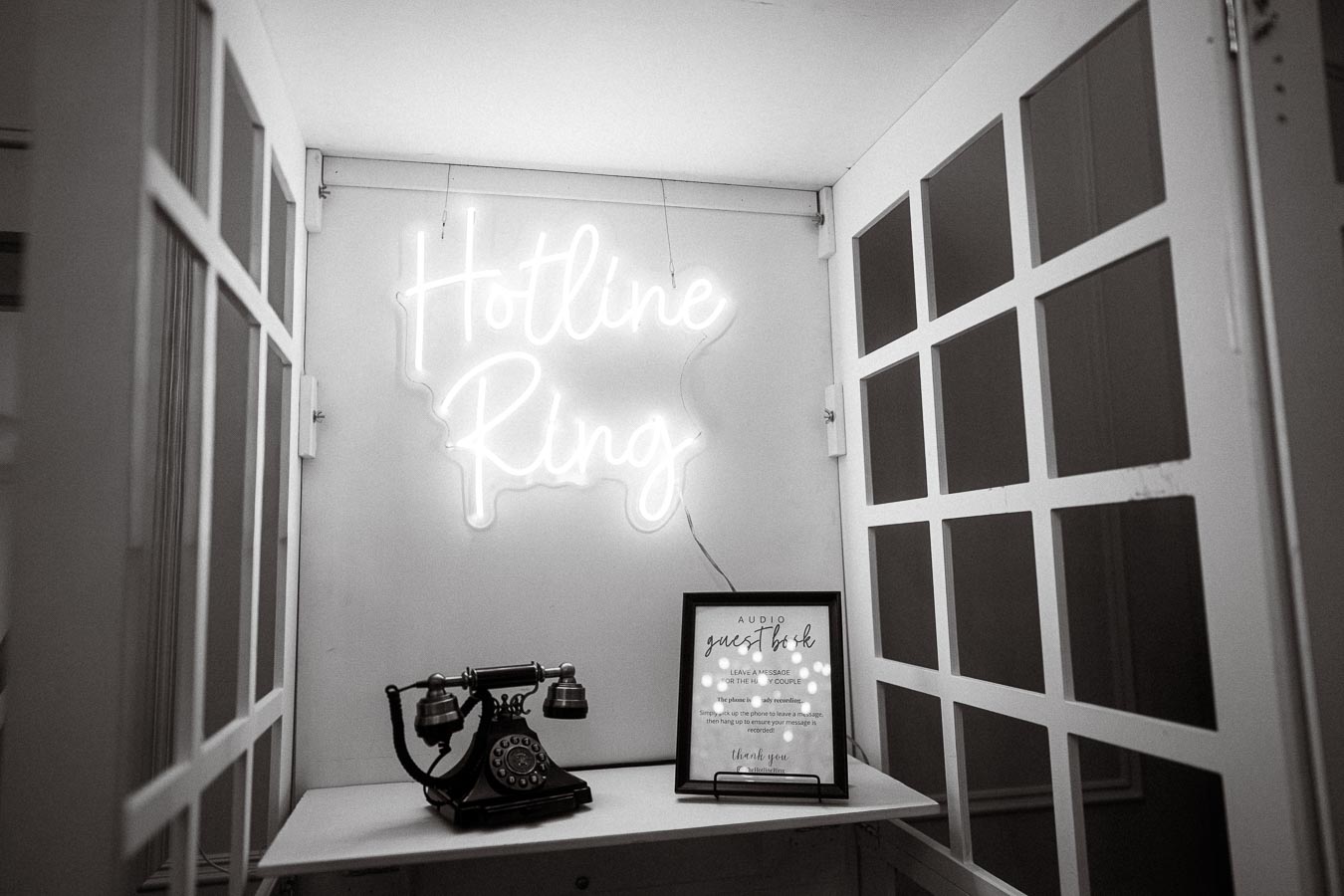 Vintage telephone setup with Hotline Ring neon sign in a modern booth.