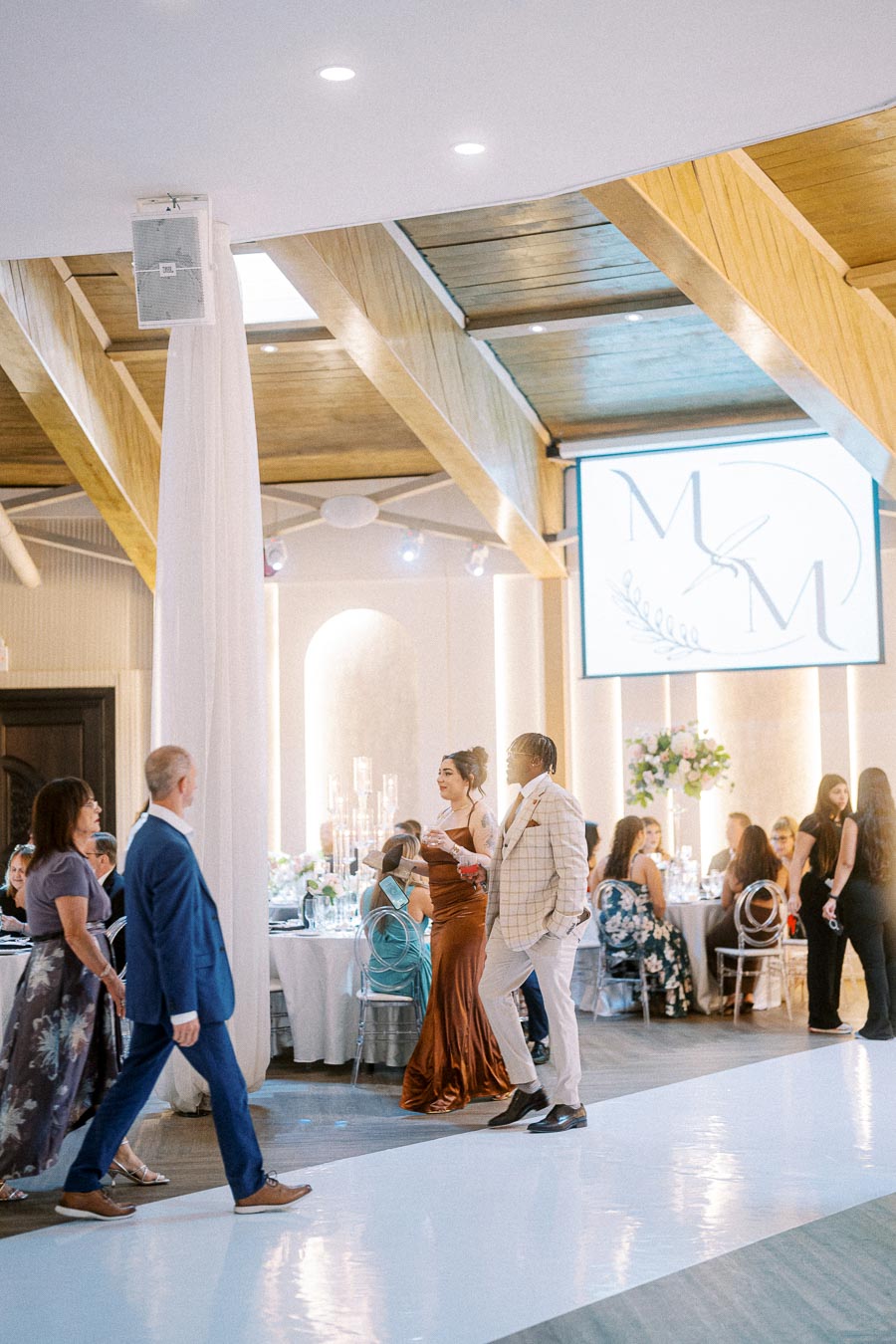 Guests mingling at an elegant wedding reception venue with wooden ceiling beams and sophisticated decor, featuring formally