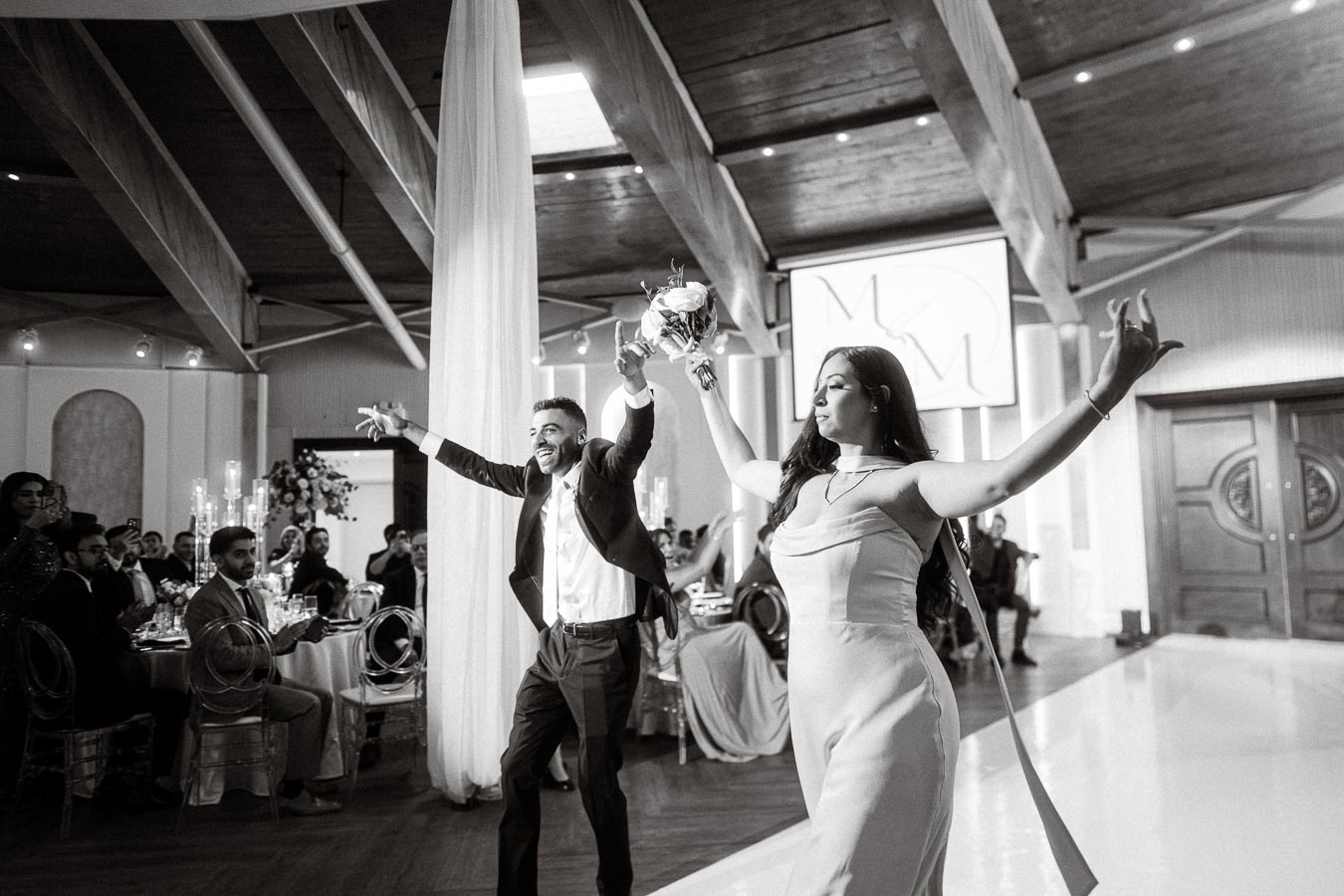 Guests celebrating at a wedding reception in a beautifully decorated venue, featuring elegant lighting and floral