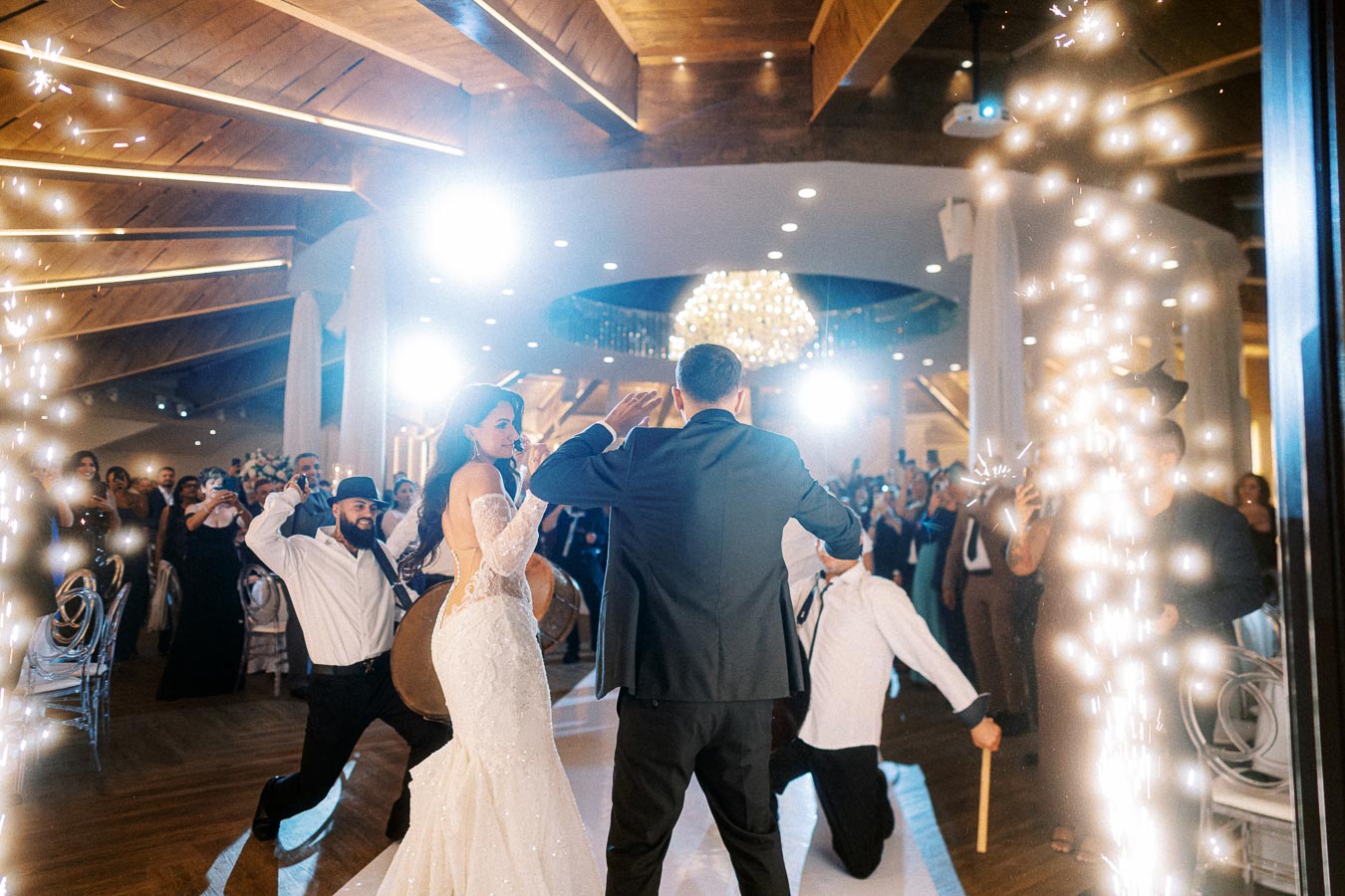 A bride and groom dancing passionately at their wedding reception, surrounded by enthusiastic guests and decorative lights,