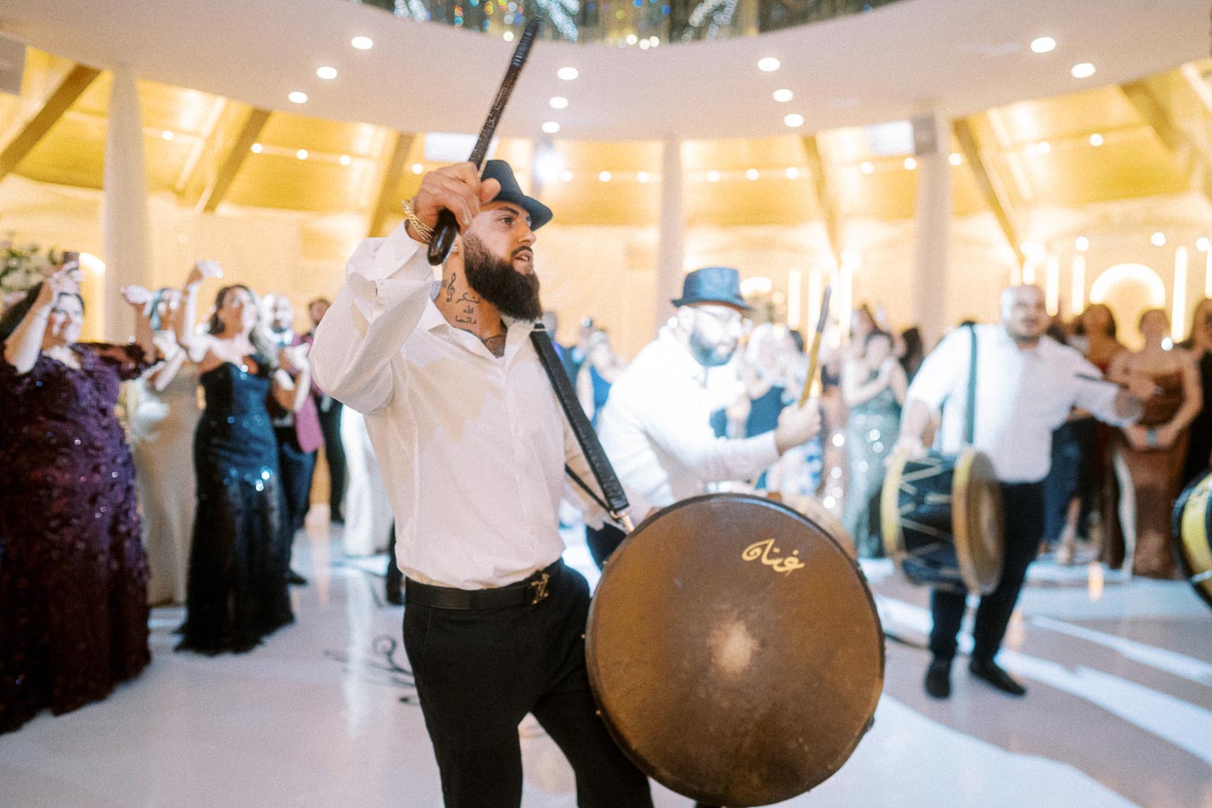 Drummers energizing a vibrant celebration at a lively indoor event, with guests dancing enthusiastically in the background,