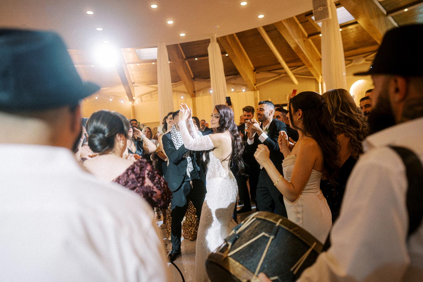 A lively wedding reception with guests dancing and celebrating in an elegant venue, featuring a drummer in the foreground