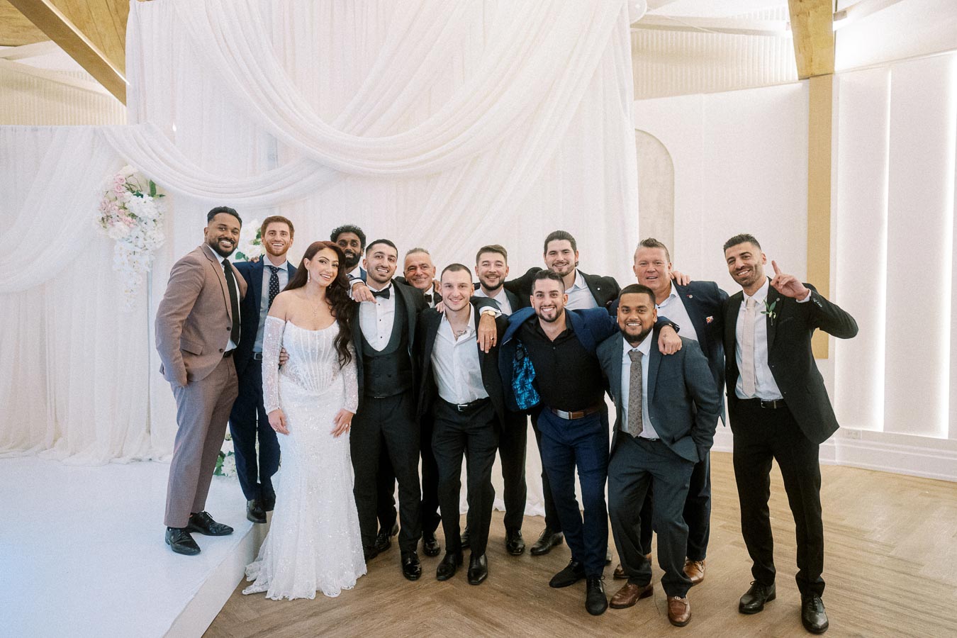 Wedding celebration with a bride in a white gown and a group of men in suits posing together in an elegantly decorated venue